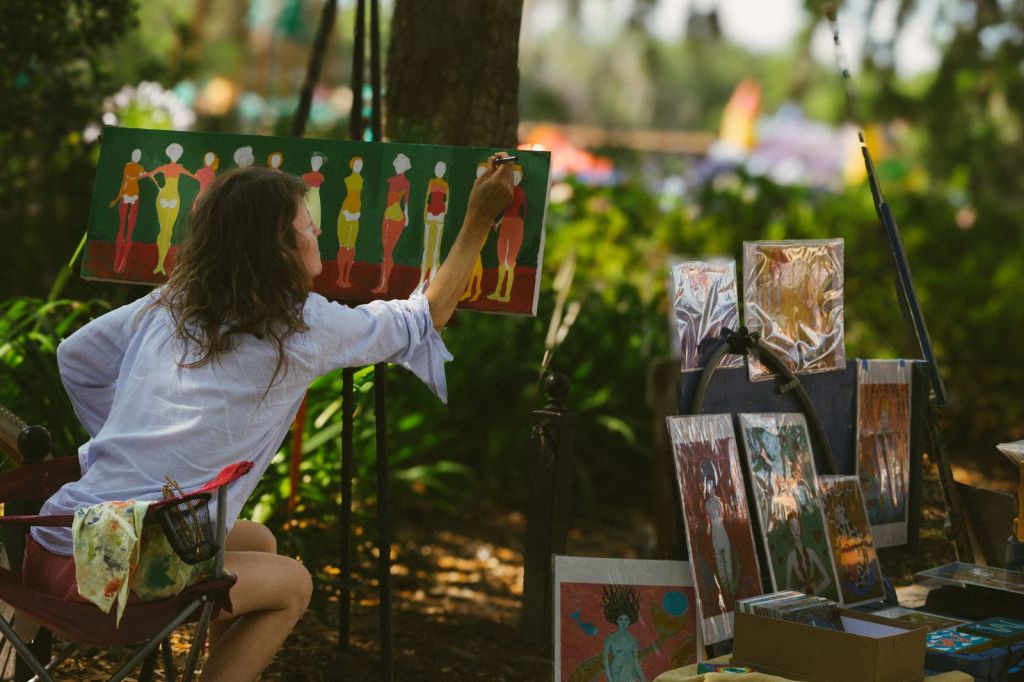 An artist paints a colorful canvas outdoors in a sunny park in Greenville, South Carolina