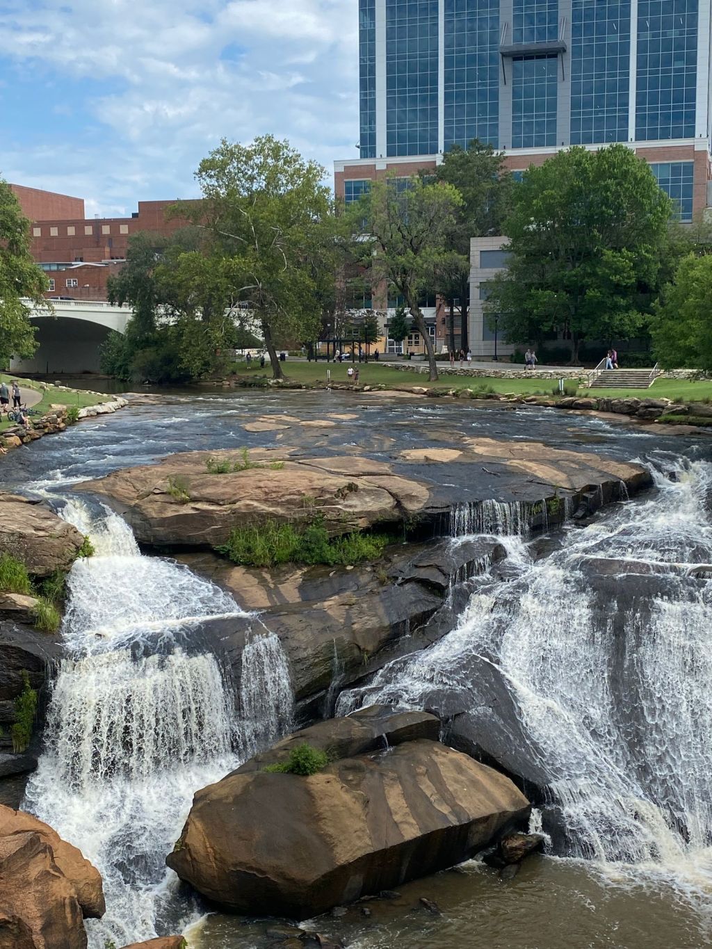 Reedy River waterfall flowing through Falls Park amid buildings in downtown Greenville, South Carolina
